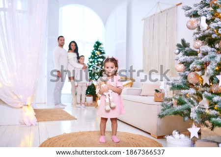 Christmas family photo session in boho style with a big tree decorated with toys and gifts. Peacock armchair wood floor white canopy and bed with macrome