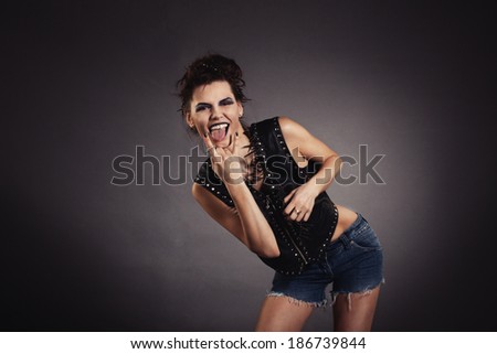 creative woman in black jacket and denim shorts showing gesture. Rocker style.