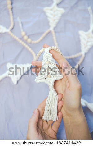 Handmade crochet new year decoration in woman hands. Person holds a christmas garland in the shape of fir tree. Decorating home for winter holidays concept