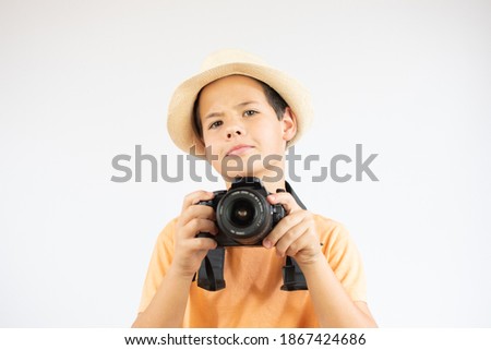 Portrait of a cheerful boy holding a camera with hat