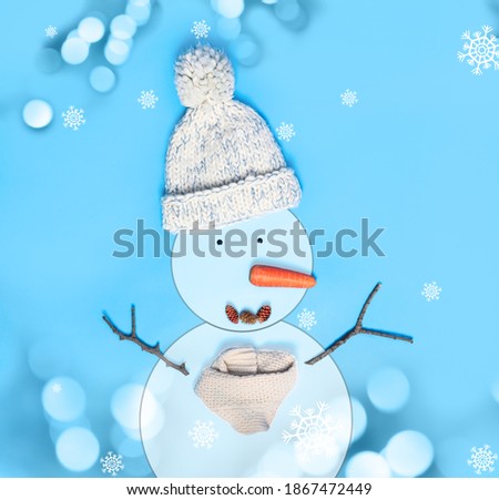 Snowman with hat and scarf on light blue background, flat lay. Bokeh effect 