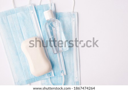 Close up top above overhead view photo of face masks hand sanitizer and bar of soap lying on white background
