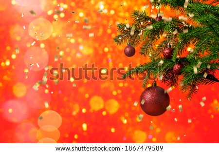 Christmas tree with decor on a red background of blurry lights and golden confetti