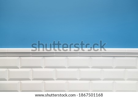 Bathroom wall design. Wall is painted in blue and tiled with white hog tiles with frieze