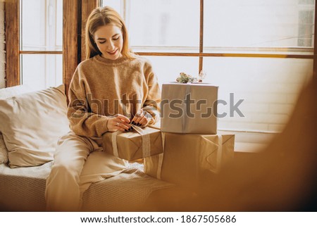 Young woman with sitting by the window with Christmas gifts
