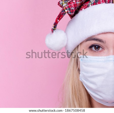 Young woman with medical mask and santa hat on pink  background. Christmas on quarantine. mask safe from coronavirus covid-19 isolated . Happy New Year celebration  merry holiday concept. portrait.  