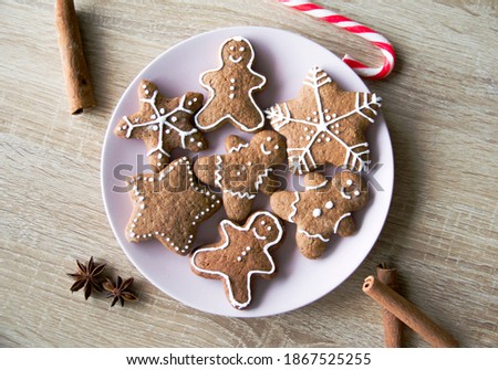 Pink plate of Christmas cookies, gingerbread men, stars and snowflakes. Kitchen wooden table. Flat layout view. Royalty-Free Stock Photo #1867525255