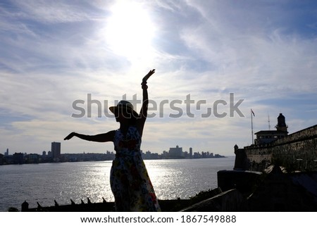 Silhouette of a woman posing a dance pose in front of the Havana bay in Havana, Cuba.