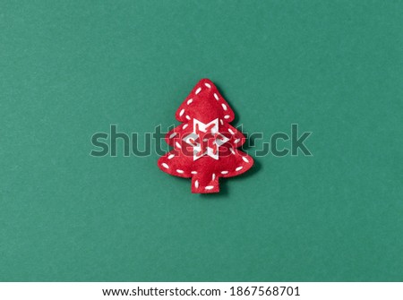 Creative Xmas minimal flat lay composition with handmade red felt Christmas tree decoration on green background. Happy New Year greeting card, postcard, invitation concept.
