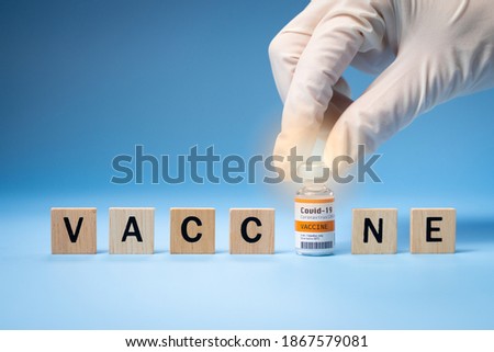 Promising Covid-19 Vaccine concept. Hand of a researcher take a 2019-nCov vaccine vial with wooden alphabet letters "VACCINE". Candidates, Authorized, Volunteers, Global trial, Hope, Successful. Royalty-Free Stock Photo #1867579081