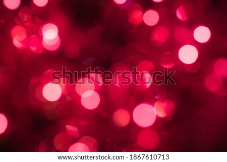 Selective focus. Garlands of glowing lights in red, pink, and lilac colors. Blurry Christmas tree background.