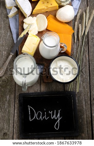 Different types of fresh dairy products on wooden background. Top view, copy space, chalkboard