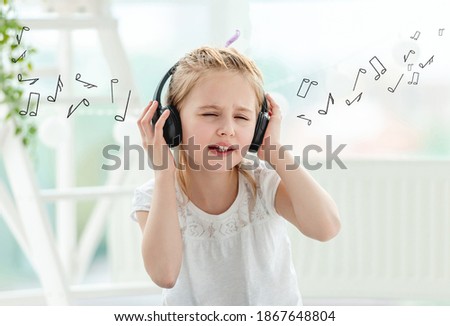 Little girl listening to music in headphones