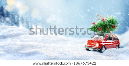 Toy car carrying christmas tree on a roof in snowy winter forest. Christmas background. Holidays card.