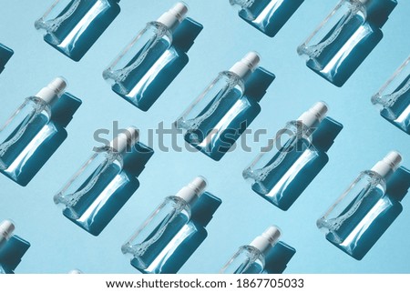 Trendy Pattern of sprays with alcoholic antiseptic, sanitizers on a blue background. Flat lay, hard shadow from the sun. Anti-virus protection concept in pandemic