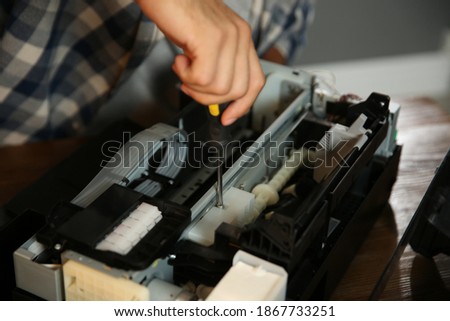 Repairman with screwdriver fixing modern printer, closeup