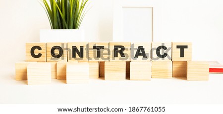 Wooden cubes with letters on a white table. The word is CONTRACT. White background.