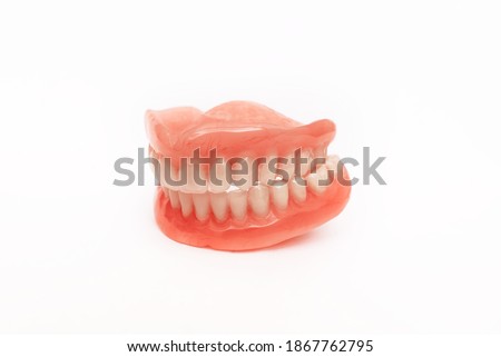 Full removable plastic denture of the jaws. Set of dentures on a white background. A side view of a dental prosthesis, isolate. Two acrylic dentures. Dentures or false teeth, close-up. Copy space