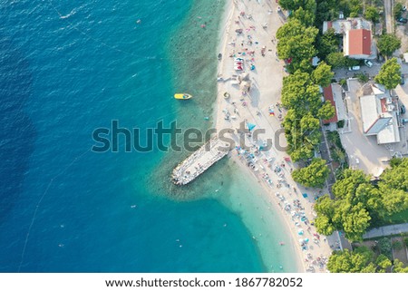An aerial shot of people enjoying the beach on a sunny day in Makarska, Croatia
