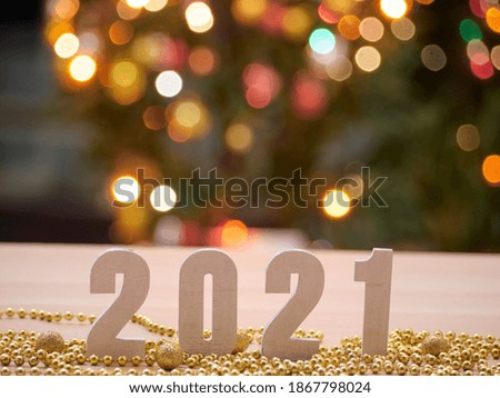 Numbers 2021 against blurred background with Christmas tree, bokeh light