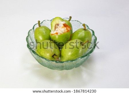 few raw olives in a green glass bowl with salt and pepper on white background.