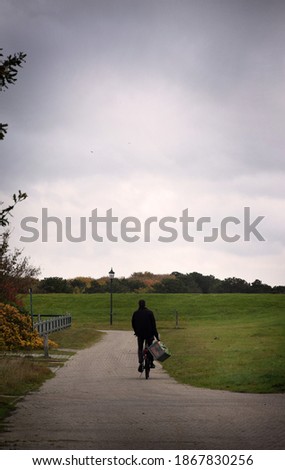 man on a bike riding down a lonley alley on a cool autumn day