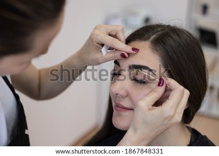 The master applies wax to depilate the hair of the eyebrows. Eyebrow correction.Wax epilation spa procedure.  Royalty-Free Stock Photo #1867848331