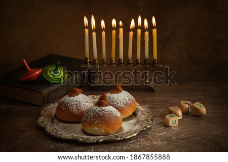 Jewish holiday Hanukkah concept and background. Hanukkah food doughnuts, candles and traditional spinning dreidel.