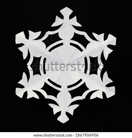 Paper snowflake on black background, close-up. Handmade new year decoration
