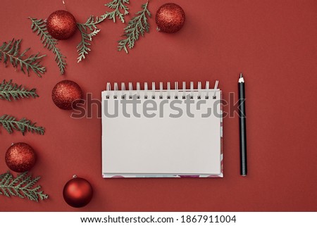 New Year's decor and a notebook in the center on a red background. Christmas decoration. Copy space, flat lay, mock up, top view.