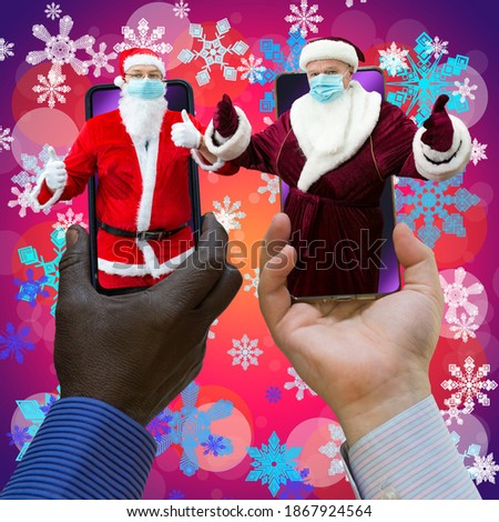 Afroamerican and caucasian-white hands holding phones with 2 Santa Clauses. Santa Clauses have medical masks on. Close-up on a pink background with snowflakes.