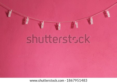 Plastic clothesline hanging over a pink - magenta wall. Copy space for additional content.  Royalty-Free Stock Photo #1867951483