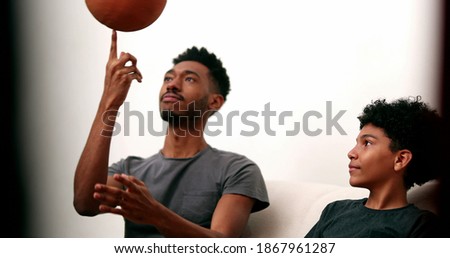 Older brother teaching younger sibling to spin basketball with finger. Two brothers bonding