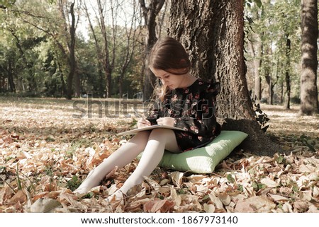 
A beautiful little girl enjoys a beautiful day, drawing in the park.