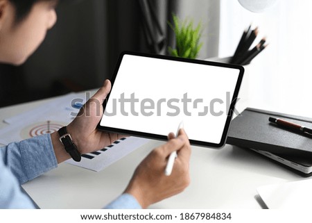 Young graphic designer with stylus pen pointing on graphic tablet with blank screen.