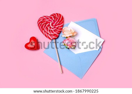 Blue envelope for a letter with pink flowers and a heart-shaped candy cane. Valentine's Day concept. Flat lay style