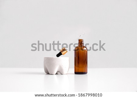 Serum, oil, acid, lotion in opened brown dropper glass with pippete on concrete pedestal side view with copy space. Spa products. Organic, natural cosmetic. Beauty, skincare concept. Stock photo