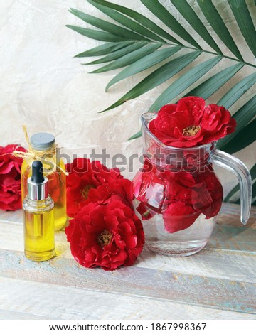 Fresh roses, water and bottles with aromatic oil on a wooden table, natural home cosmetics, skin care ingredients, healthy lifestyle, alternative medicine