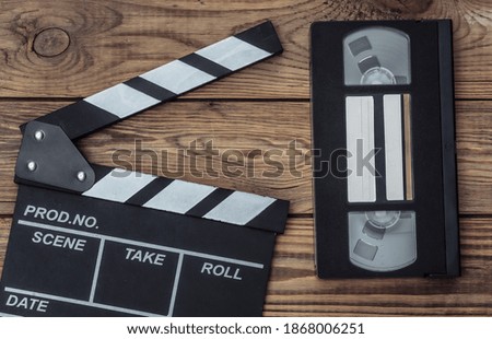 Movie clapper board and video cassette on wooden background. Cinema industry, entertainment. Top view