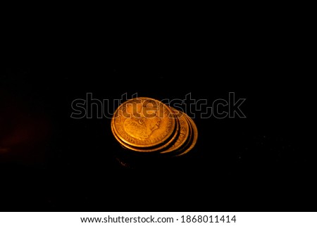 A pile of illuminated old coins with 1 Peso (Spain,1897) coin on top on dark background