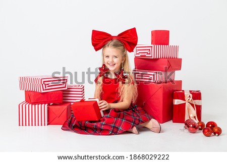 cute little girl is being considered for Christmas. white background, large gift boxes, space for text. The concept of Christmas