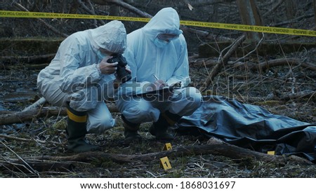 Detectives are collecting evidence in a crime scene. Forensic specialists are making expertise. Police investigation in a forest. Royalty-Free Stock Photo #1868031697
