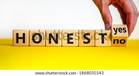 Honest symbol. Hand turnes a cube and changes the words 'honest no' to 'honest yes'. Beautiful yellow table, white background. Copy space, business and honest concept.