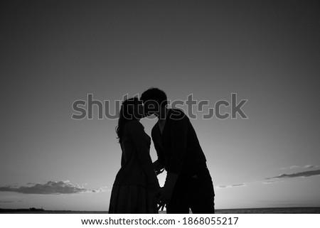 Silhouette of a young girl and her boyfriend kissing against the blue sky with clouds at sunset.  Lovers in nature.Lovers silhouette. Magic moments of loving hearts.
Young couple in love outdoor.