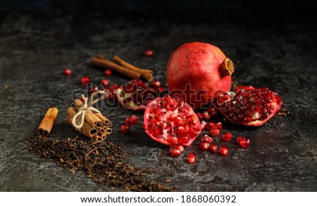 Still life photo of pomegranade and cinamon aromated dry tea leafs on the grunge background