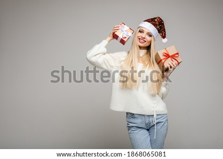 funny woman with christmas hat sits with a big red box and think what is inside, picture isolated on white background