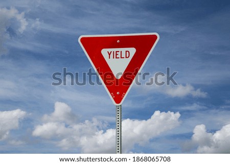 Yield sign on blue sky background (north American road sign)