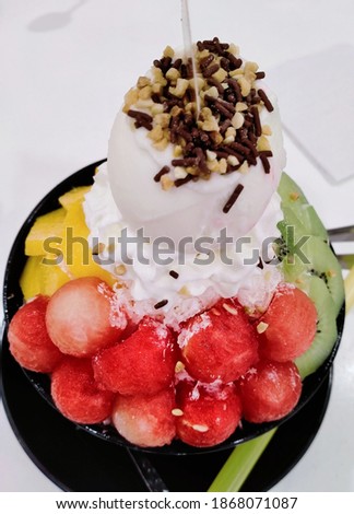 AN IMAGE OF A BINGSU. Bingsu is a popular Korean shaved ice dessert with sweet toppings that may include chopped fruit, condensed milk, fruit syrup, and red beans. 