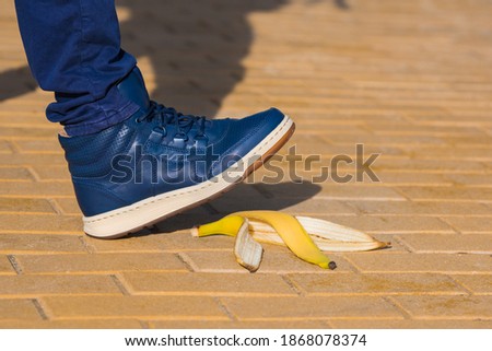 Man stepping on slippery banana skin or peel. About to slide with a banana peel. Unexpected accident concept Royalty-Free Stock Photo #1868078374
