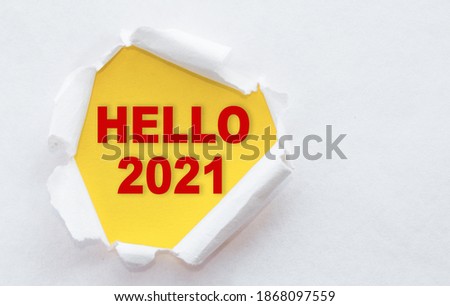 Top view of white torn paper and the text HELLO 2021 on a yellow background.